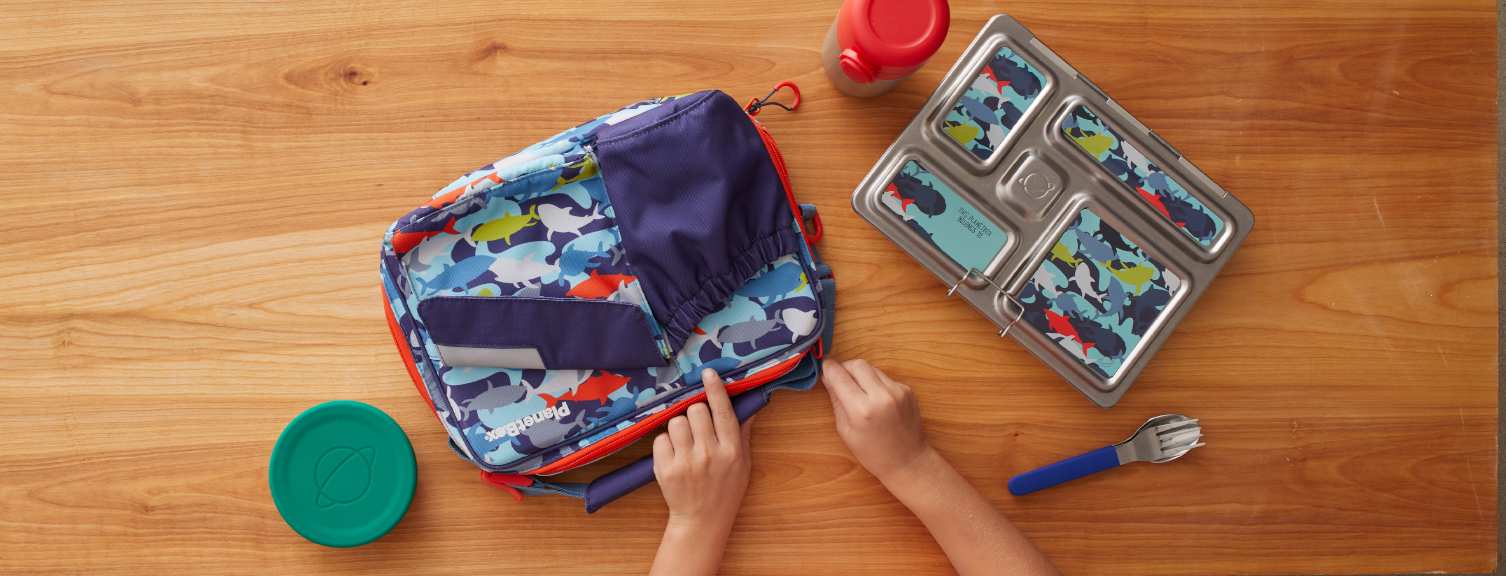 Camo shark carry bag and rover lunchbox on wood background