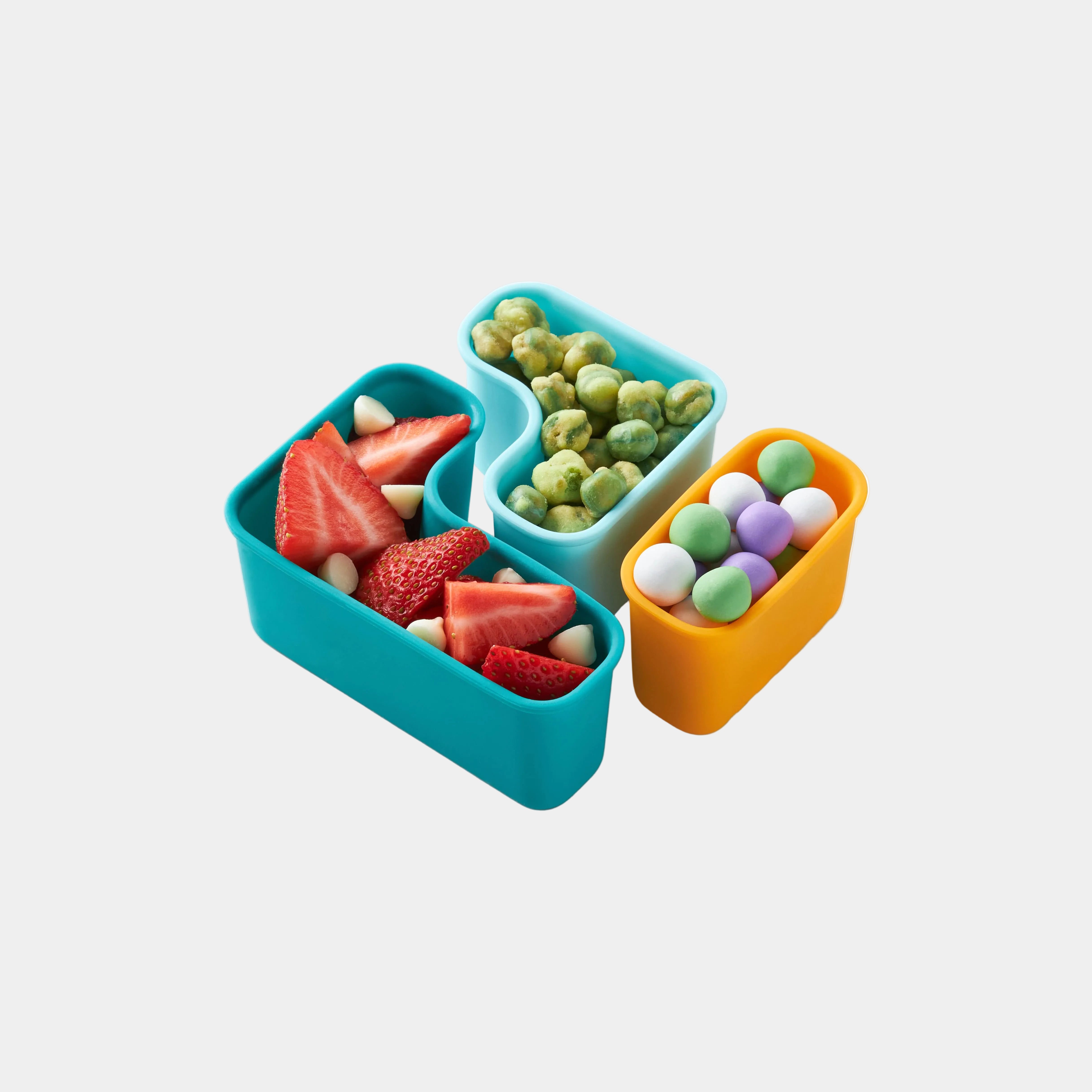 Teal, light blue and yellow puzzle pods on white background filled with strawberries, wasabi peas and pastel yogurt drops.