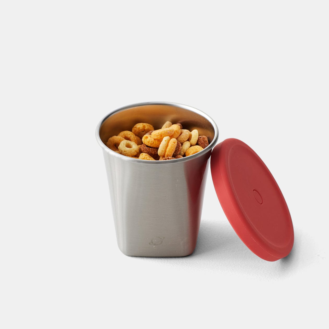 Stainless steel cup with cheerios, and red lid from the straw and lid set positioned to the side.