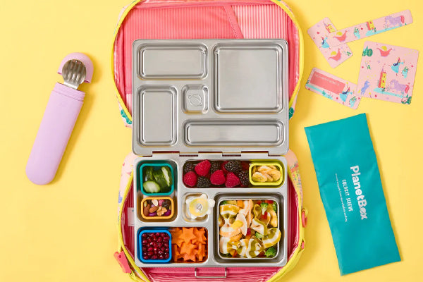 PlanetBox Accessories assortment including snack packs and dig-in utensil on yellow background.