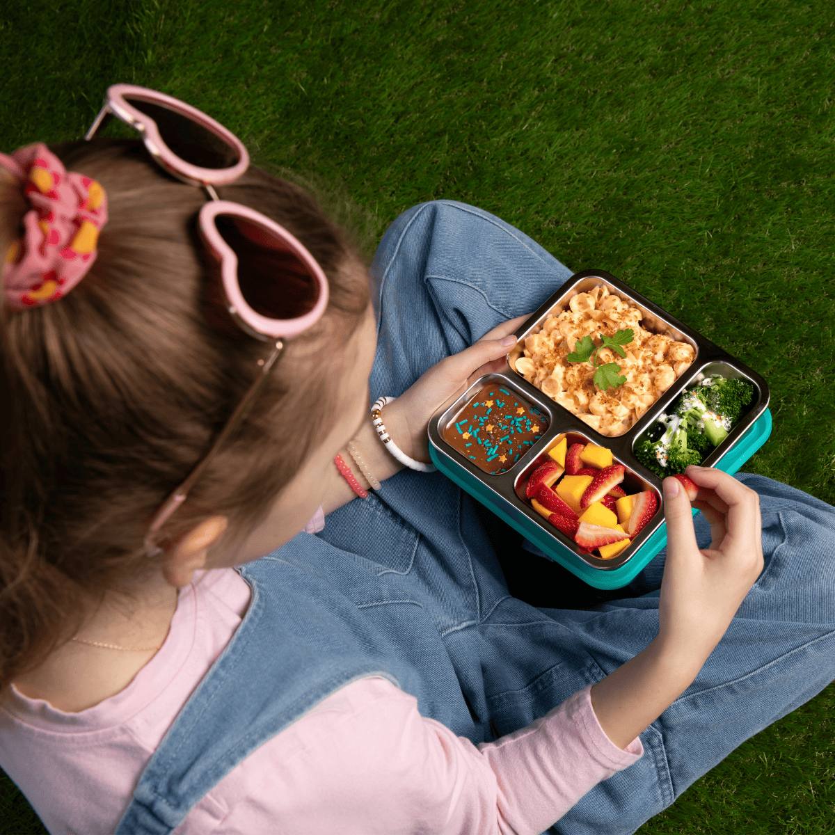 Child holding a voyager box with food on grass