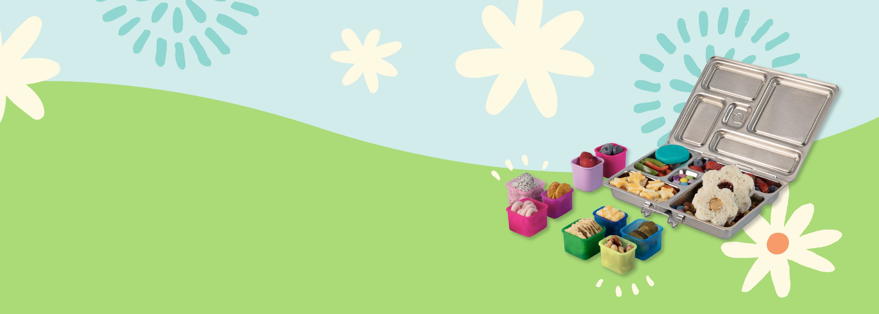 Children's lunchbox with snacks and toys on a green field with flowers