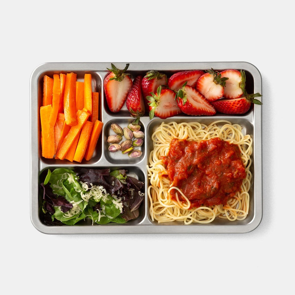 Top down shot of plated rover tray. Clockwise: Carrot sticks, strawberries, Spaghetti with red sauce, salad, and pistachios in small treat compartment. 