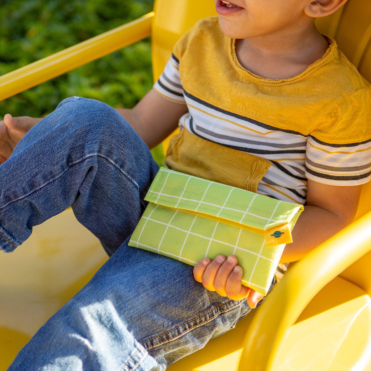 Child holding larger size Snack Pack in Blossom in one hand, and pulling sandwich out with the other.
